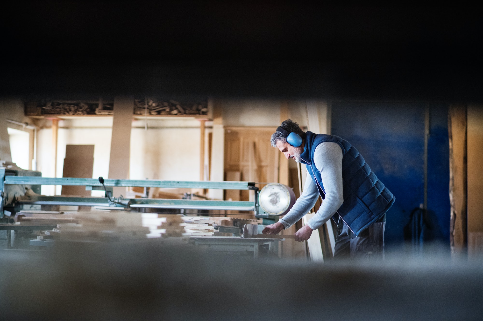 A man worker in the carpentry workshop, working with wood.