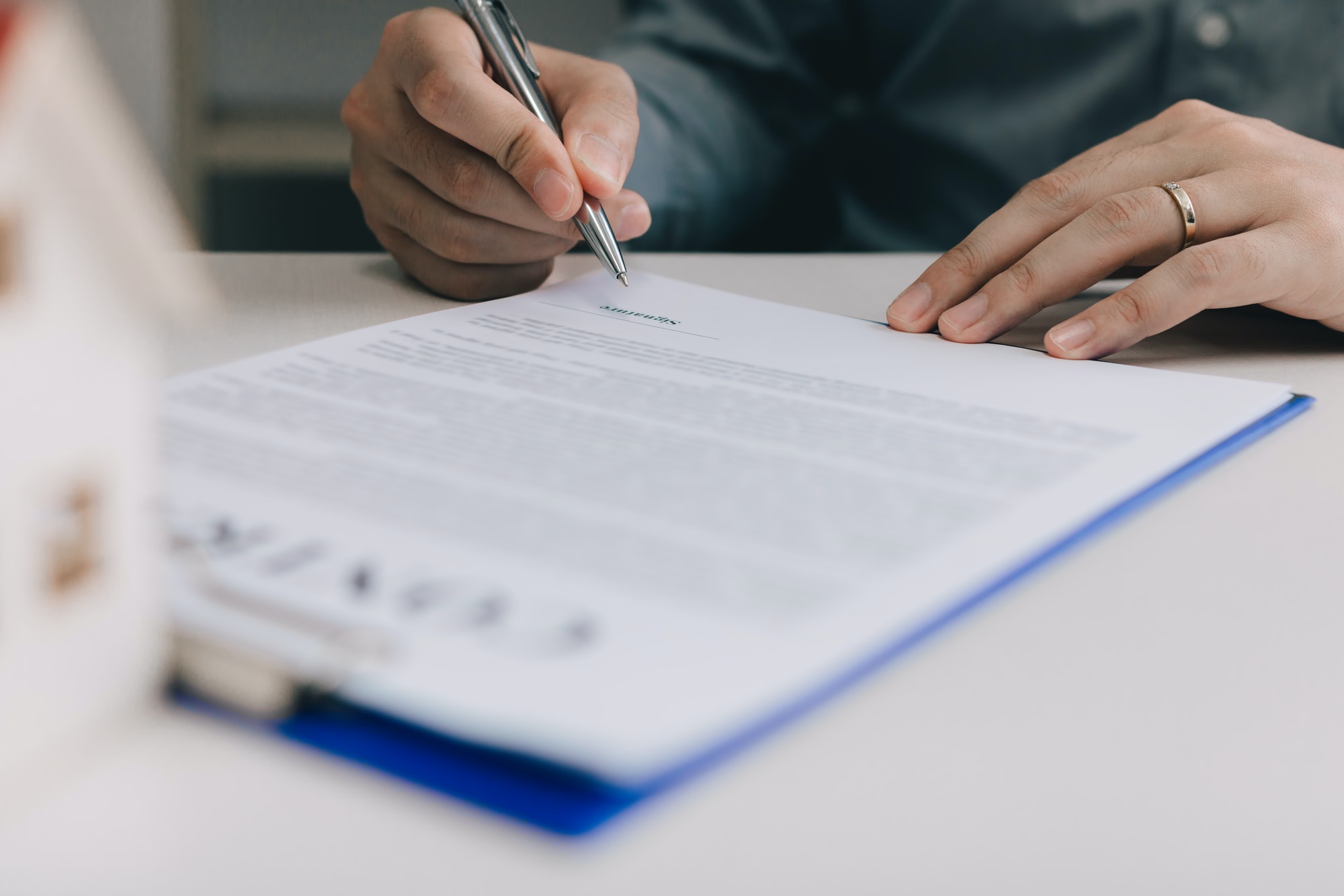 Close up hand man signing paper contract agreement for buying house.